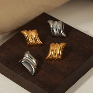 Textured gold and silver square earrings with wrinkled finish and beaded center on wood