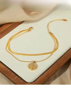 Détail d'une chevillère double couche plaquée or 18K avec pendentif pièce sur satin