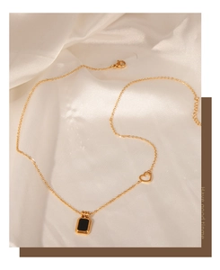 Close-up of gold chain necklace with black rectangular pendant and heart detail
