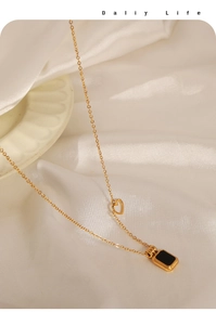 Detail of gold titanium steel necklace with black acrylic plate and heart charm detail