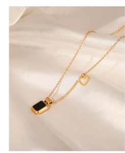 Detail of gold-plated necklace with black rectangular tag and hollow heart pendant