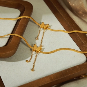 Golden titanium steel butterfly anklet with matte pendants and tassel on light background