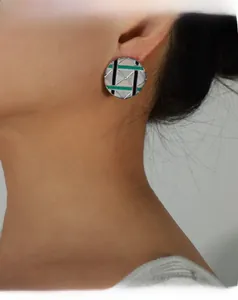Detail of round pyramid earring with green enamel and geometric textured engraving