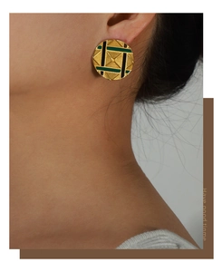 Close-up of vintage gold pyramid pattern earrings with green and black enamel details