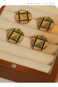 Detail of round gold-plated earrings with green and black enamel and pyramid texture