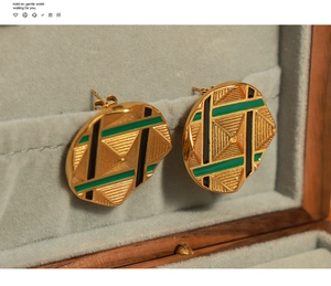 Detail of round gold-plated stud earrings with green enamel and geometric engraving