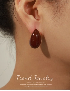 Close-up of a glossy dark brown teardrop earring in copper with 18k gold plating