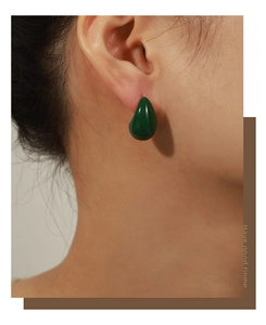 Detail view of model wearing dark green teardrop earrings with 18k gold plating finish