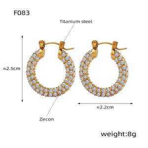 Détail macro de boucles d'oreilles en acier titane doré incrustées de zircons brillants
