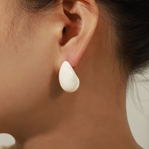 Modern white enamel teardrop earrings in 18k gold plating shown on a female model