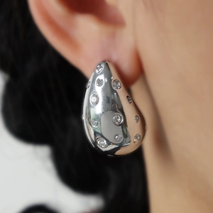 Close-up of silver teardrop earrings featuring sparkling inlaid crystals on a model
