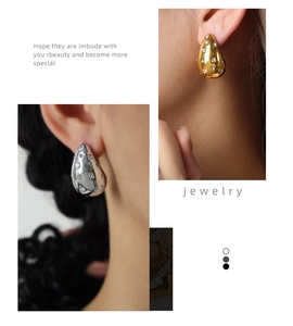 Macro detail of chunky teardrop earrings with crystals in gold and silver finish
