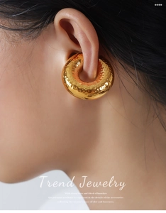 Close-up of chunky gold-plated hammered doughnut earrings on a model for a trendy look