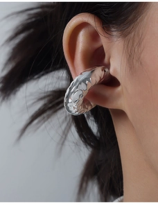 Detail of silver irregular hammered ear cuff showing modern textured metal design on ear
