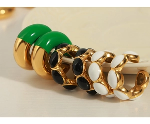 Detail of 18K gold plated enamel earrings in green black and white colors on a ceramic tray