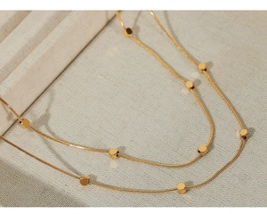 Vue macro d'un collier chaîne serpent dorée avec des détails de perles cubes polies
