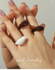 Close-up of trendy coffee and white enamel drip rings with a fluid design on hands