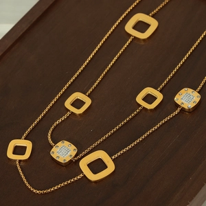 Lange geometrische Pulloverkette mit vergoldeten Quadraten und Pavé-Kristallen auf Holztablett