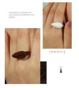 Detail view of teardrop enamel rings in white and dark brown on gold plated band
