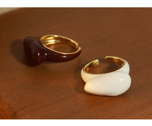 Detail of irregular geometric open rings with brown and cream enamel on gold-plated metal