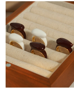 Detail of vintage teardrop enamel rings in wood box with gold plated open design
