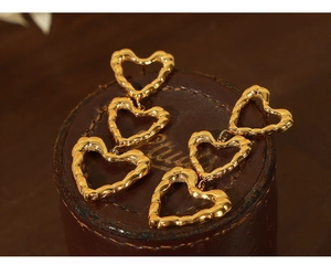 Detailed view of triple hollow heart dangle earrings with gold bamboo texture design