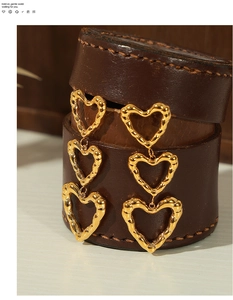 Macro detail of triple hollow heart earrings in gold-plated steel with hammered texture