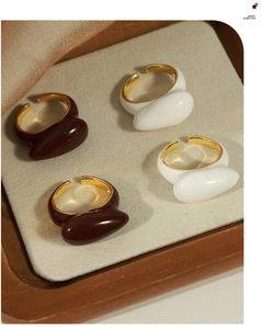 Detail of adjustable open rings in white and dark brown enamel with gold plating finish