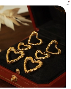 Detail of gold triple heart drop earrings with bamboo texture on jewelry box