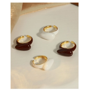 Detailed top view of four adjustable gold-plated rings with white and brown enamel finish