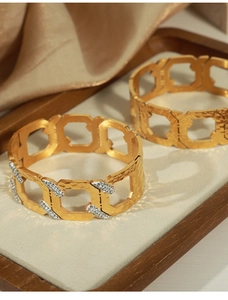 Detail of gold geometric hollow bracelets with hammered texture and cubic zirconia accents
