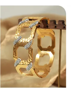 Close-up of gold geometric C-shaped bangle with micro-pave zircons and hammered finish