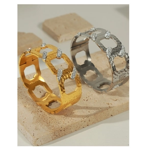 Detail of gold and silver geometric C-shape bracelets with hammered metal and zircon stones
