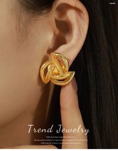 Close-up of a model wearing a large 18k gold plated knot stud earring with a woven design