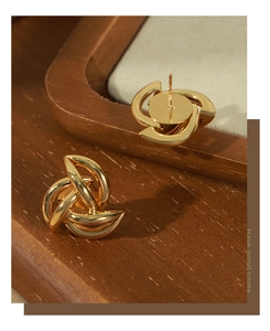 Detailed view of twisted knot gold hoop earrings on a vintage wooden jewelry stand