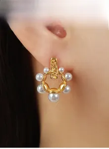 Détail d'une boucle d'oreille dorée avec perles dégradées portée par un mannequin