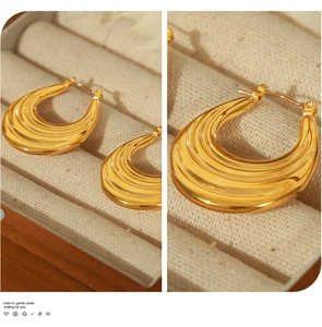 Macro detail of gold plated hoop earrings with sleek vertical grooved textures