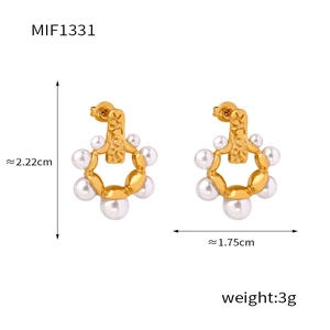 Détail de boucles d'oreilles dorées avec texture martelée et perles blanches
