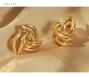 Macro shot of 18k gold plated knot earrings on elegant silk fabric background