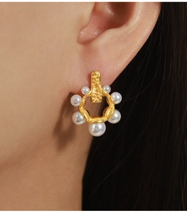 Gros plan sur boucle d'oreille vintage dorée avec perles et texture métal martelé