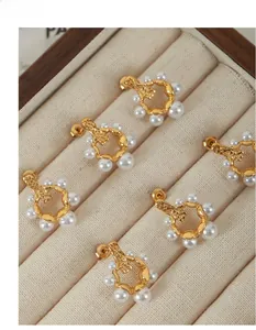 Détail de boucles d'oreilles vintage dorées avec perles dégradées sur boîte à bijoux beige