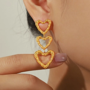 Gold heart drop earrings with bamboo texture worn by a model in a close-up shot