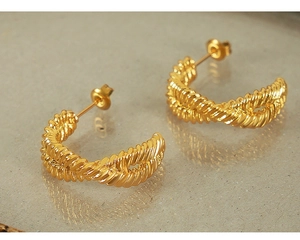 Close-up of golden twisted rope texture C-shaped hoop earrings with polished finish