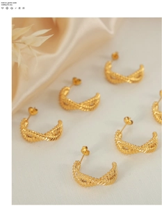 Detailed view of gold twisted C-shape hoop earrings on elegant silk background