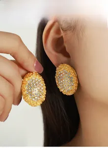 Macro shot of French style gold oval honeycomb earrings with pearls and crystal inlay