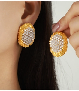 Detailed close-up of oval gold hammer-textured earrings with cluster pearl inlay on model