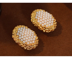 Detailed macro view of vintage oval honeycomb earrings with pearls and gold-plated metal texture