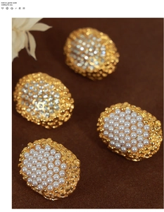 Macro shot of gold-plated oval stud earrings with shell pearls and textured lava finish