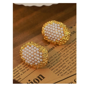 Close-up of vintage oval gold earrings featuring central pearl inlay on a retro background