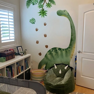 Détail de stickers dinosaure aquarelle vert avec feuilles dans une chambre d'enfant